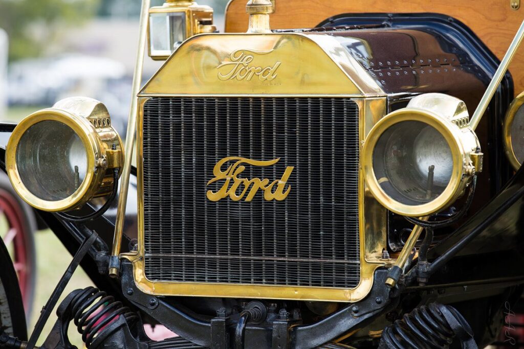 Polished brass radiator and headlamps of an early Ford with the Ford script across the grille