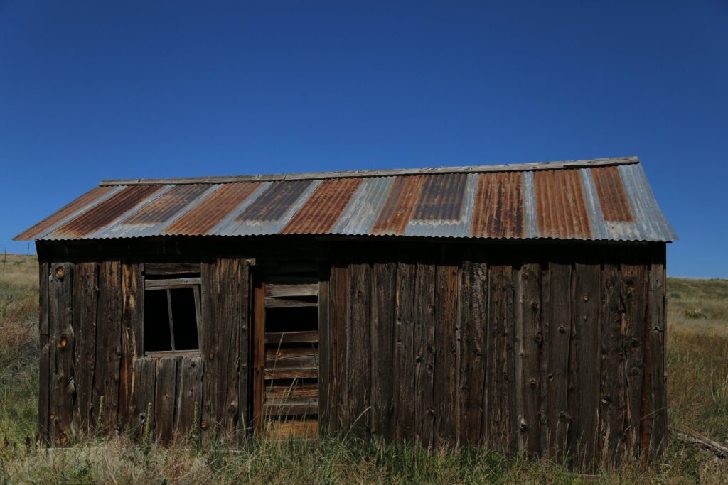 Weathered wooden shack with a rusty corrugated tin roof under a deep blue sky