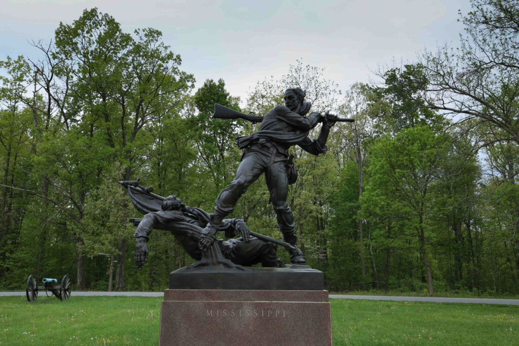 Bronze Confederate soldier swinging his musket like a club over a wounded flag bearer, on a granite base engraved Mississippi