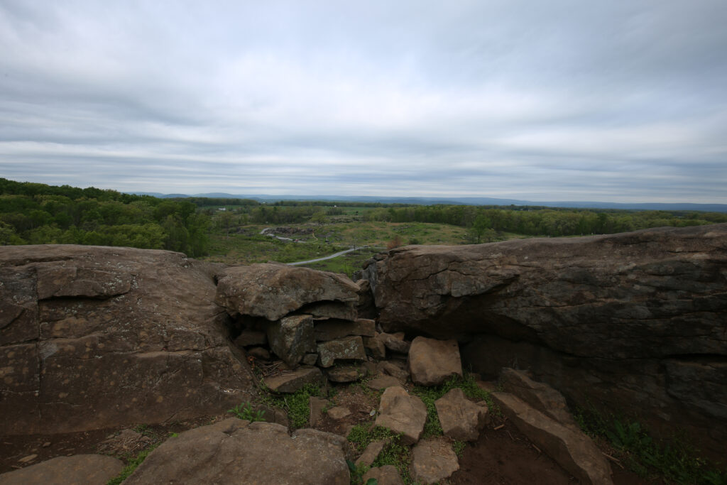 Large rock outcrop on Little Round Top with a hand-stacked stone breastwork, overlooking wooded valley and farmland