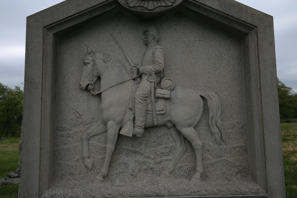 Granite relief carving of a Union cavalryman on horseback on the face of a regimental monument
