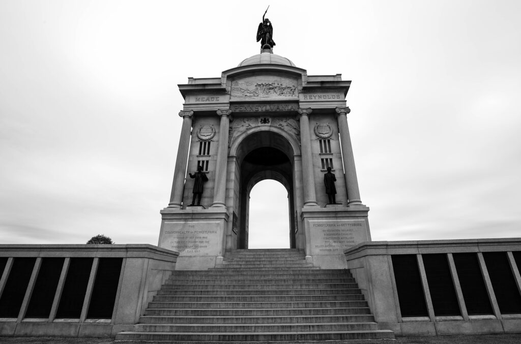 Black and white view up the steps of the Pennsylvania State Memorial, a domed granite arch topped by a bronze goddess