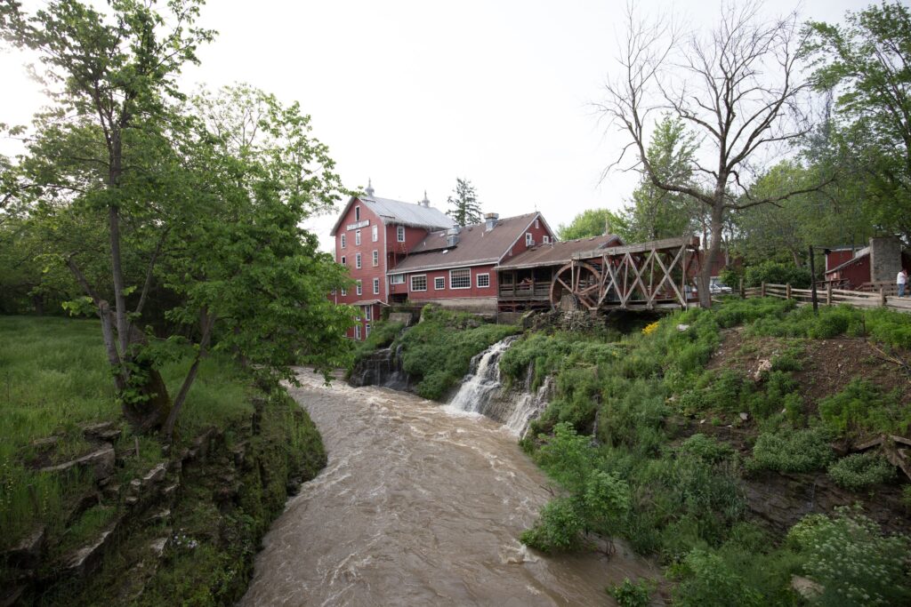 Wide view down the Little Miami gorge, with the river curving below Clifton Mill and its waterfall