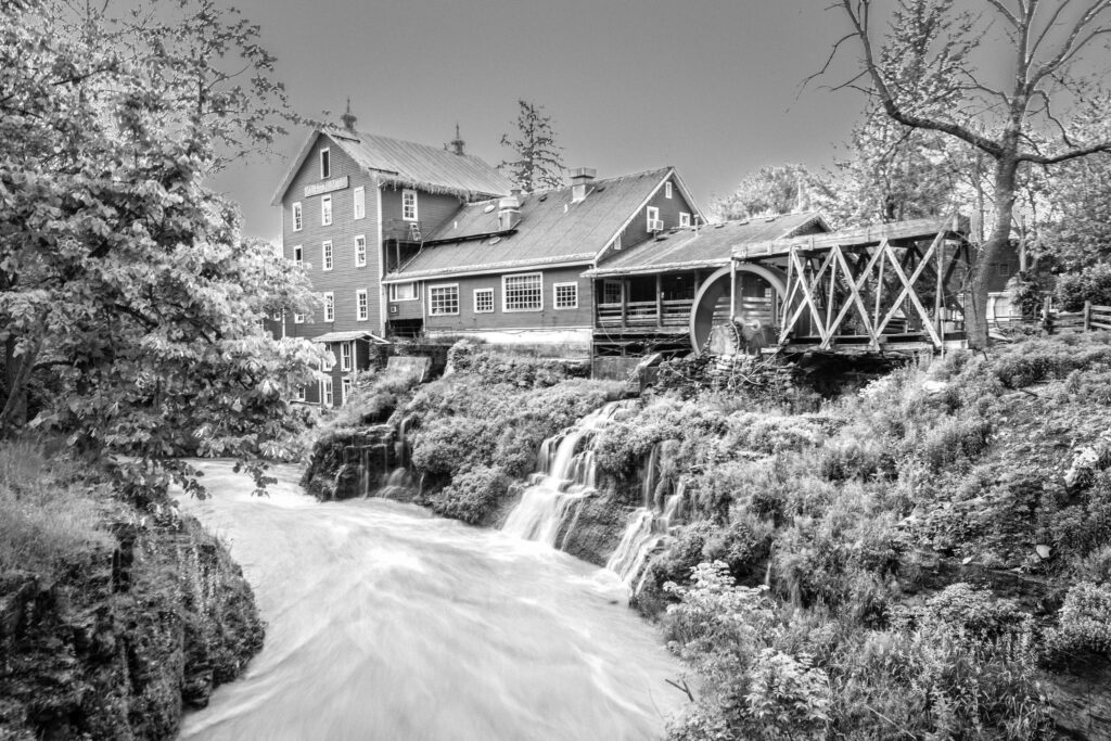 Black and white long exposure of Clifton Mill above silky white waterfalls in the gorge