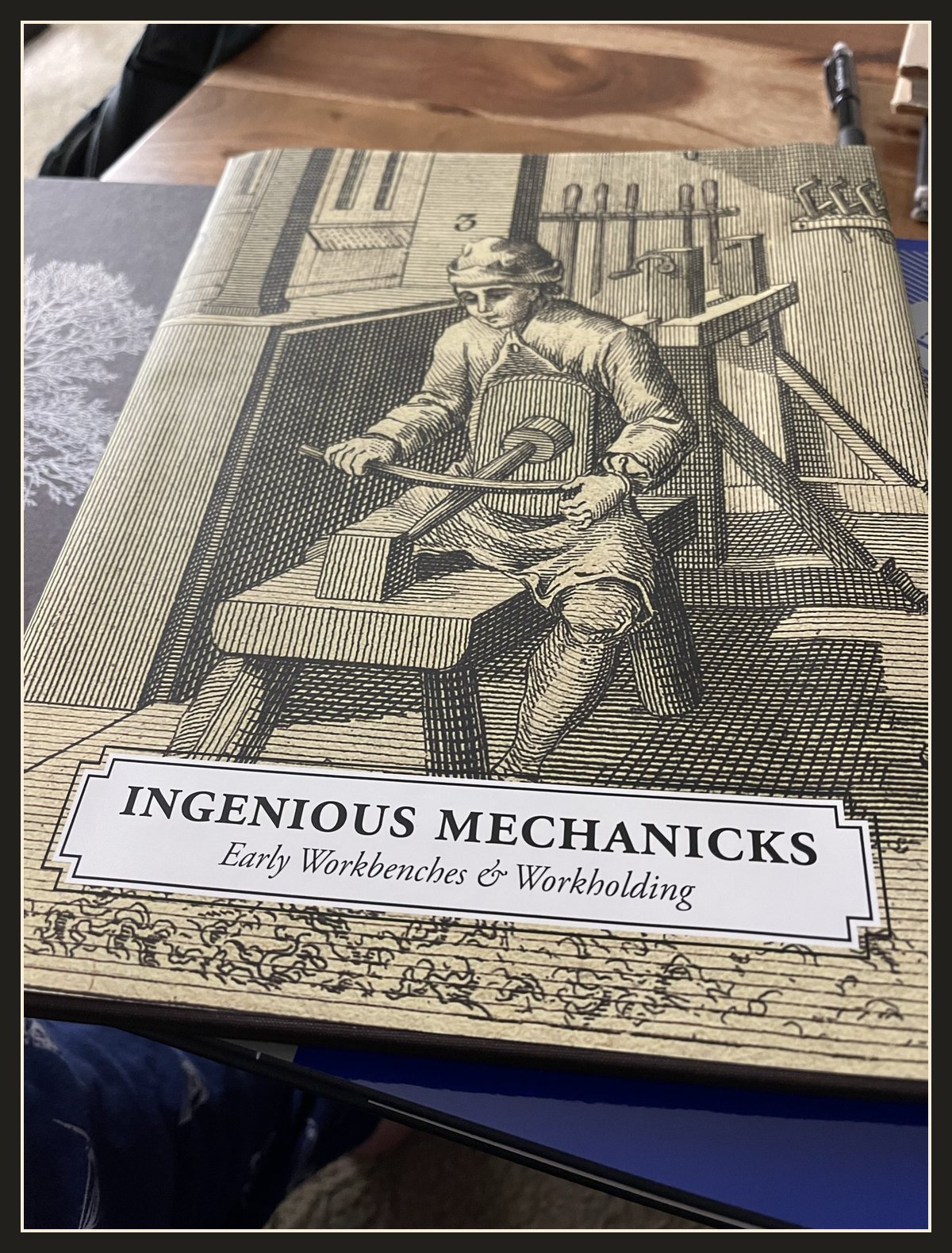 Adam's copy of Ingenious Mechanicks: Early Workbenches & Workholding, with an old engraving of a craftsman at a low bench on the cover.
