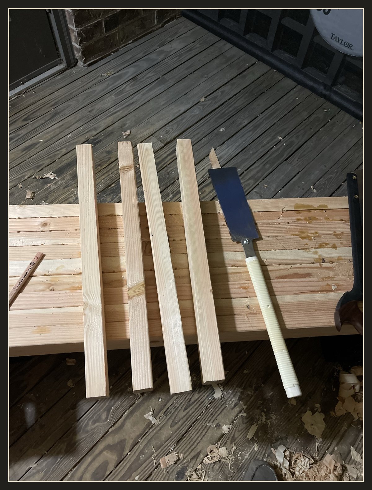 Four leg blanks lined up across the slab, with a Japanese pull saw beside them.