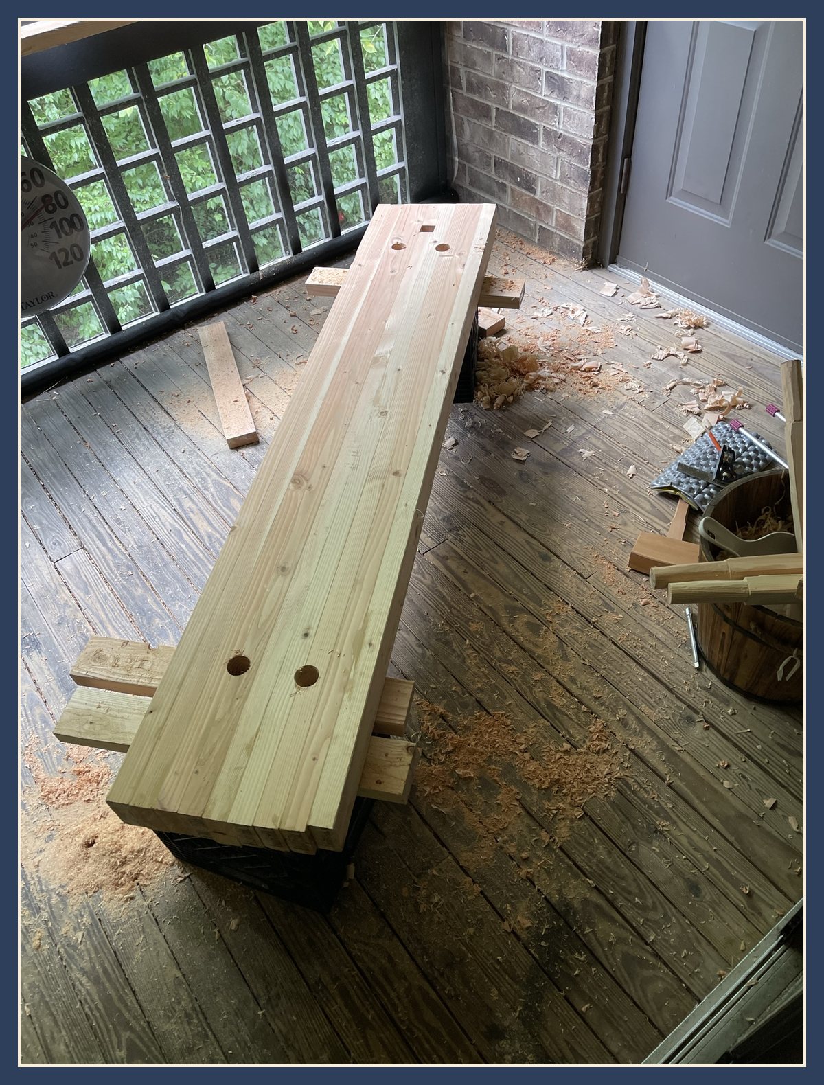 The bench slab on the porch with two angled holes bored through one end.