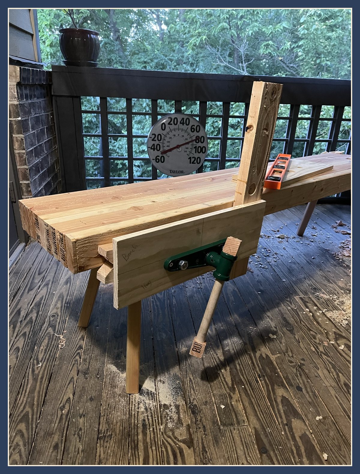 The bench with a wooden vise jaw and green vise hardware mounted at one end.