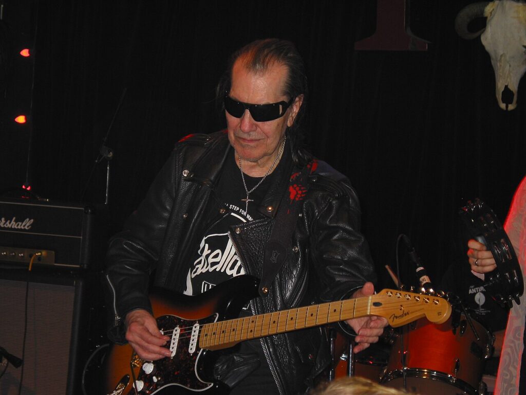 Link Wray in sunglasses and a leather jacket, playing guitar